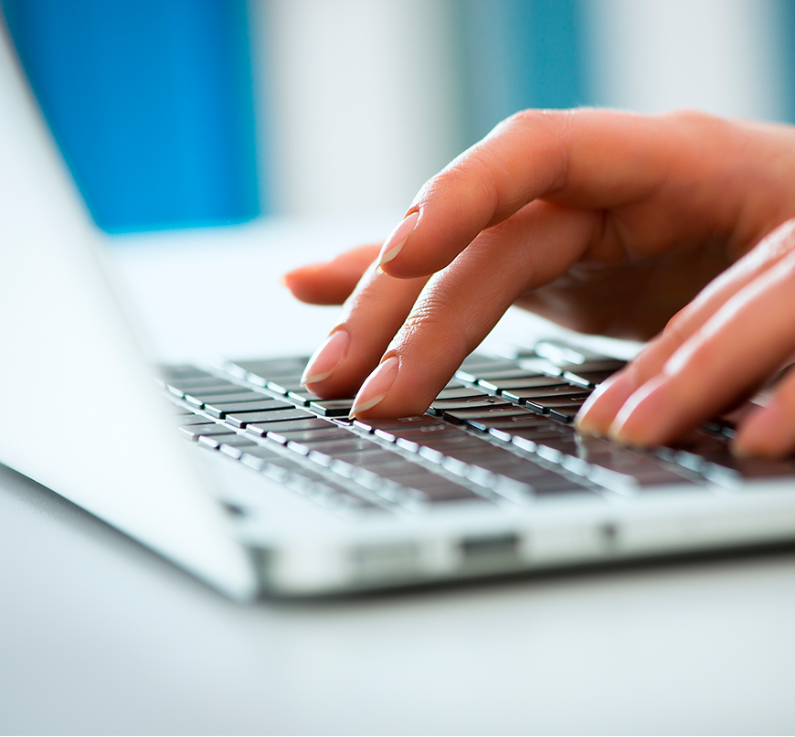 Close-up of a person's hands typing on a laptop keyboard